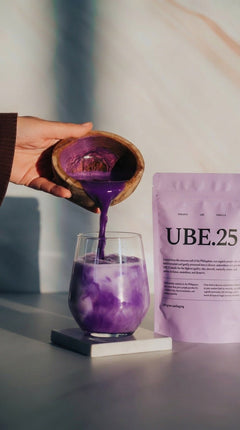 Ube poeder wordt in een glas melk geschonken, UBE.25 zakje ernaast